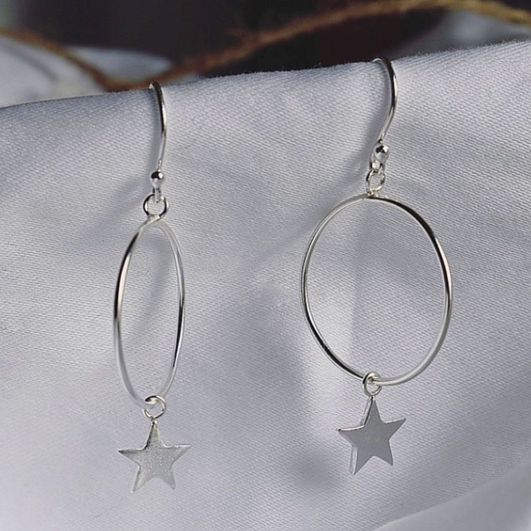 Two silver hoop earrings with hanging star charms