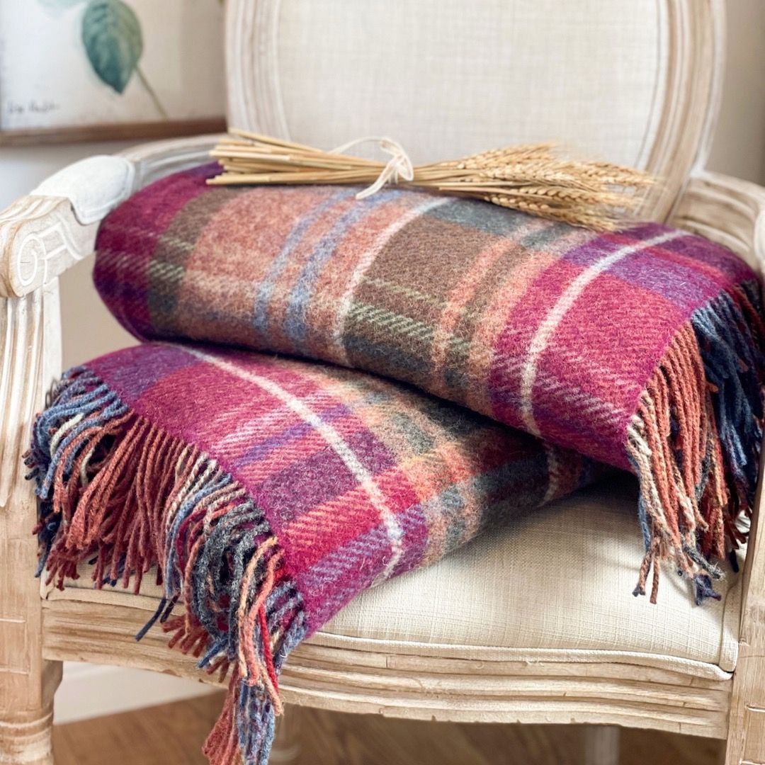 two tartan blankets laying on top of a cream chair topped with a bunch of barley