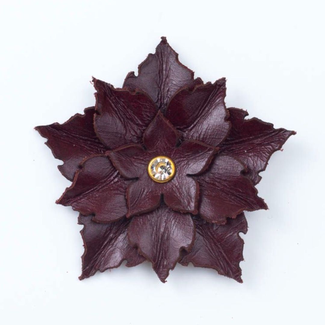 A dark burgundy leather flower  brooch with a clear crystal center
