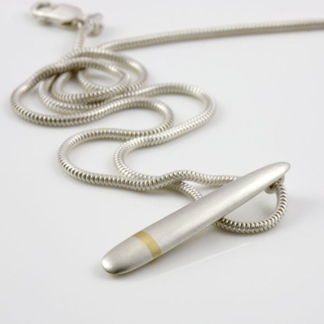 a matte sterling silver lode pendant with a matte gold inlay at its base on a necklace