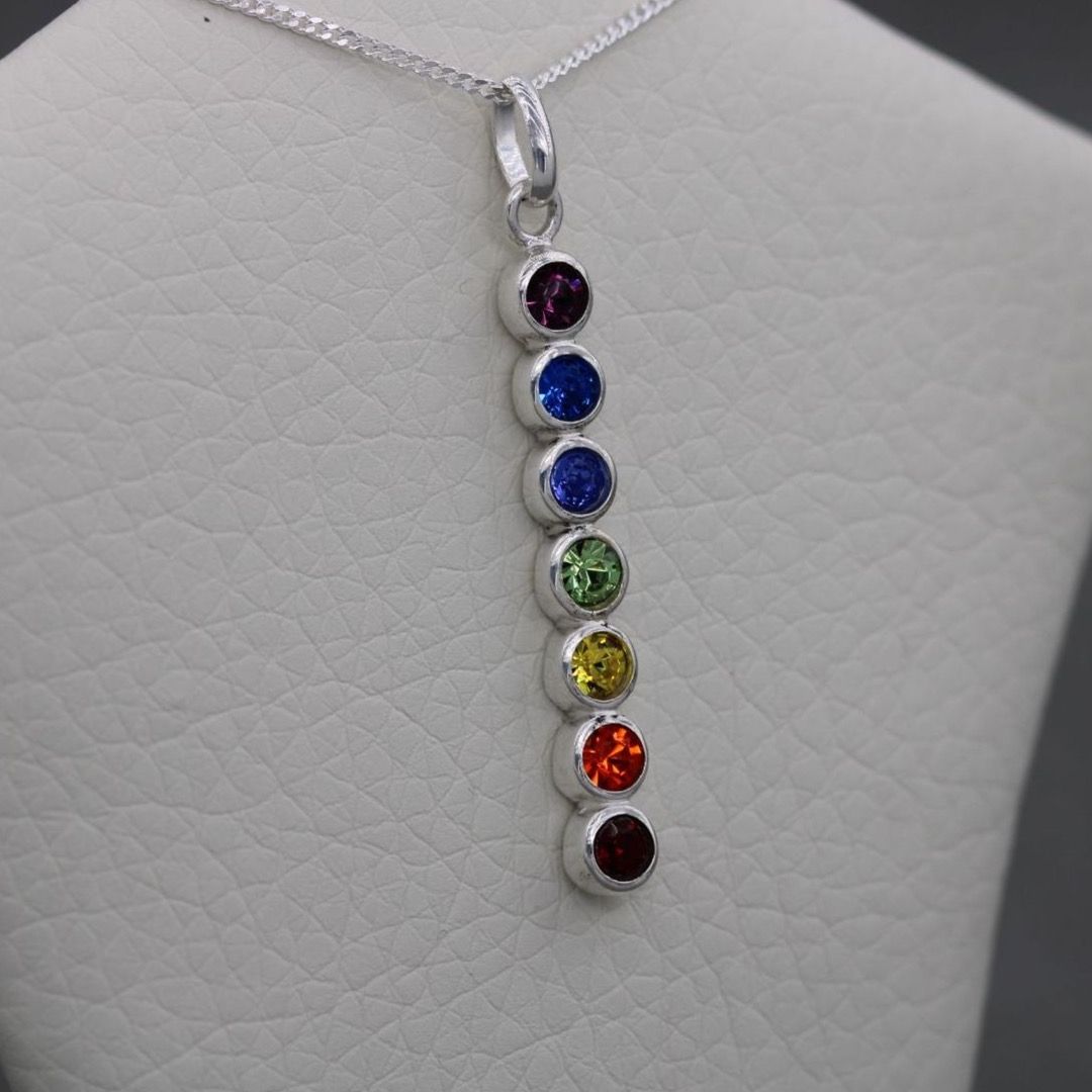 Several different coloured stones hanging in sequence from a necklace in a rainbow effect