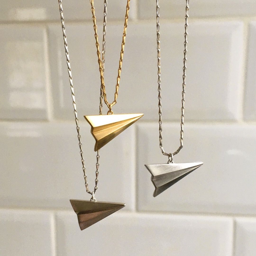 Three paper plane necklace charms in silver and gold