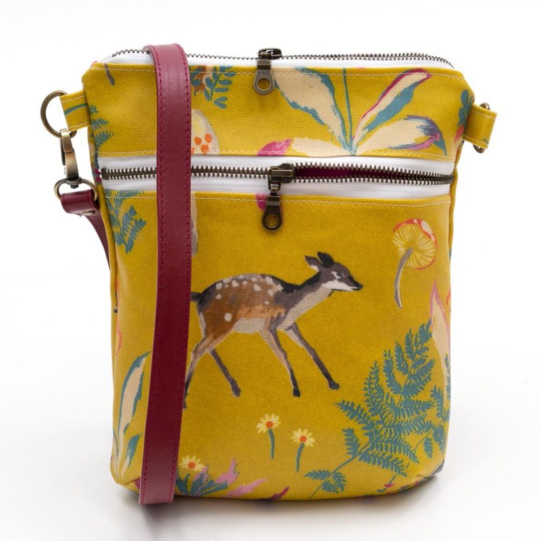 A laminated yellow shoulder bag featuring a deer and woodland patterns