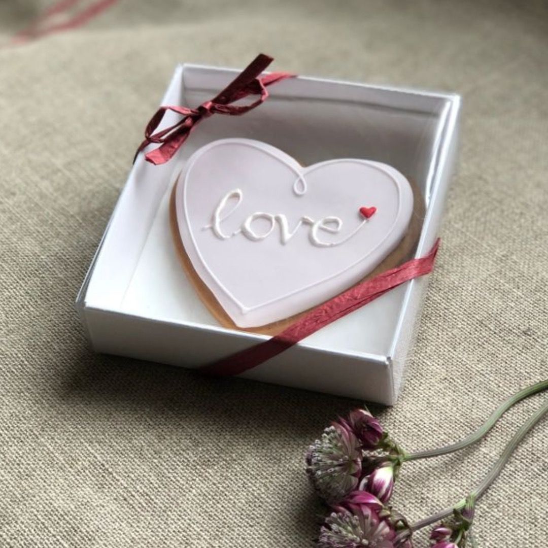heart shaped biscuit with blush pink icing with "love" written on it