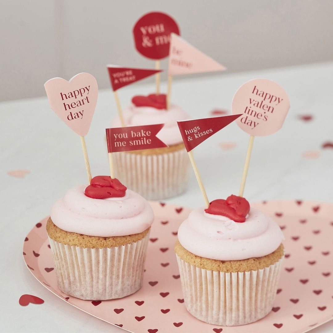 Cake topper flags of assorted shapes in pink and red with heartfelt messages written on them