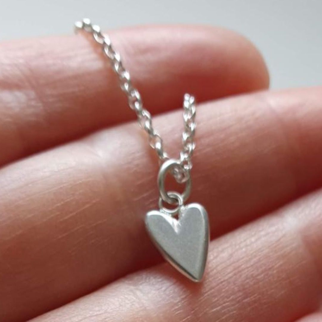 A small sterling silver heart pendant on a dainty chain