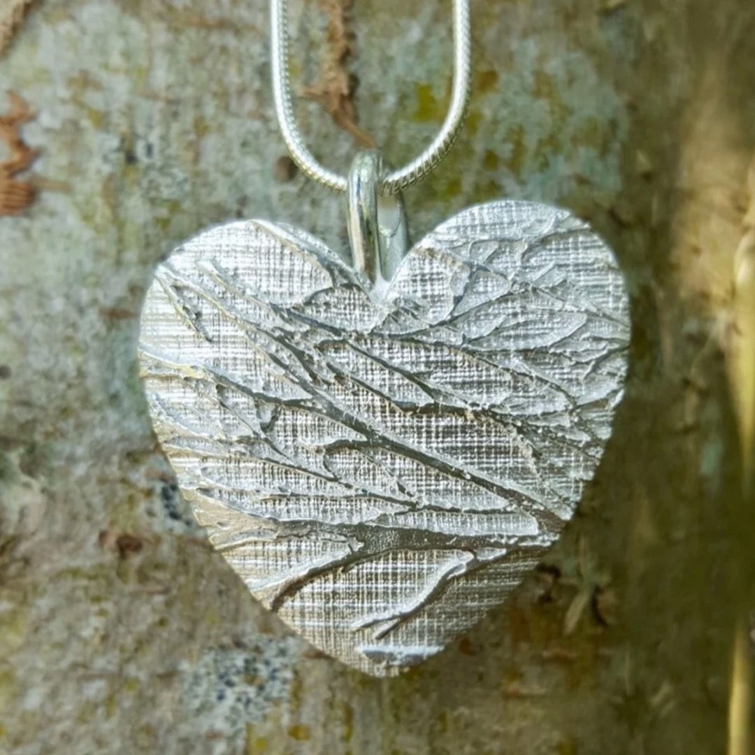 A sterling silver heart shaped pendant embossed with birch branches and texture