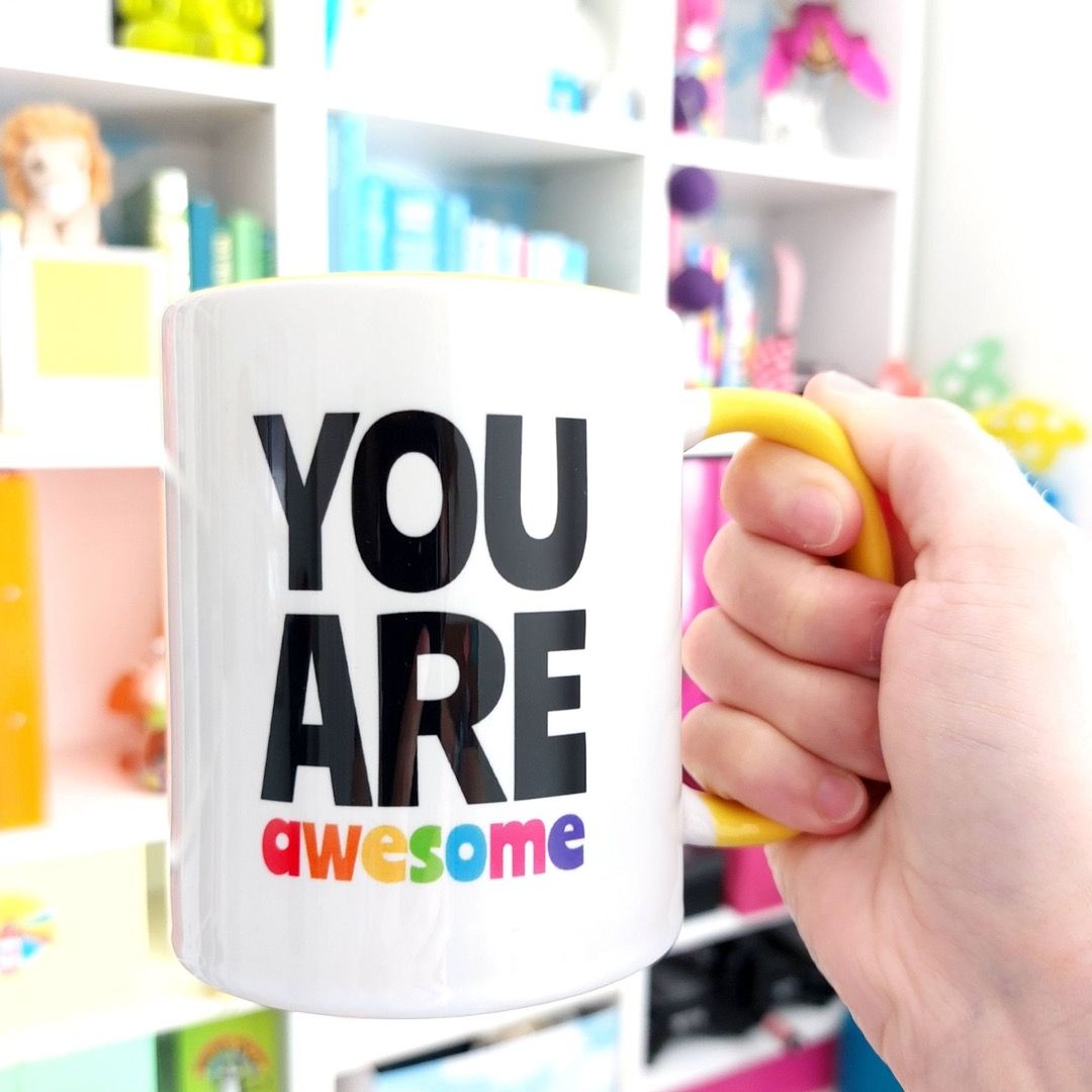 A yellow handled mug featuring "You are Awesome" in rainbow text