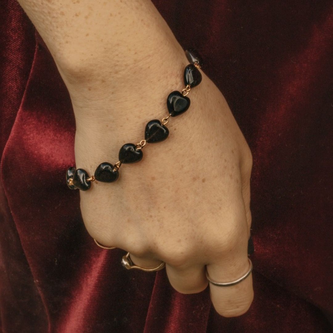 a bracelet made of polished black obsidian hearts with a gold chain link