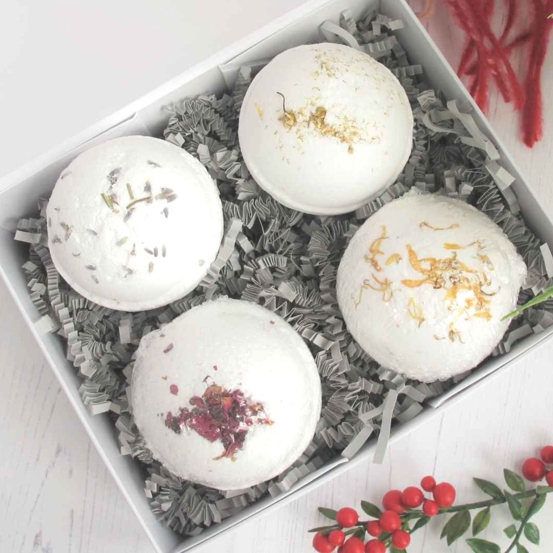 Four white bath bombs in a gift box infused with different dry petals