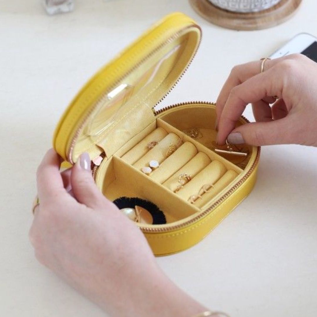 A bright yellow, oval shaped jewellery box with two deep side pockets and several ring holders