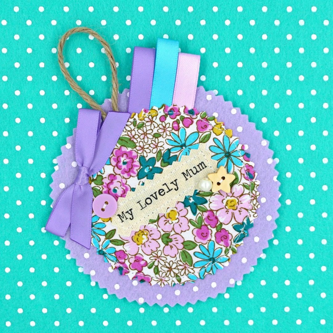 A floral ditsy badge in pinks, purbles and blues that says "My Lovely Mum"
