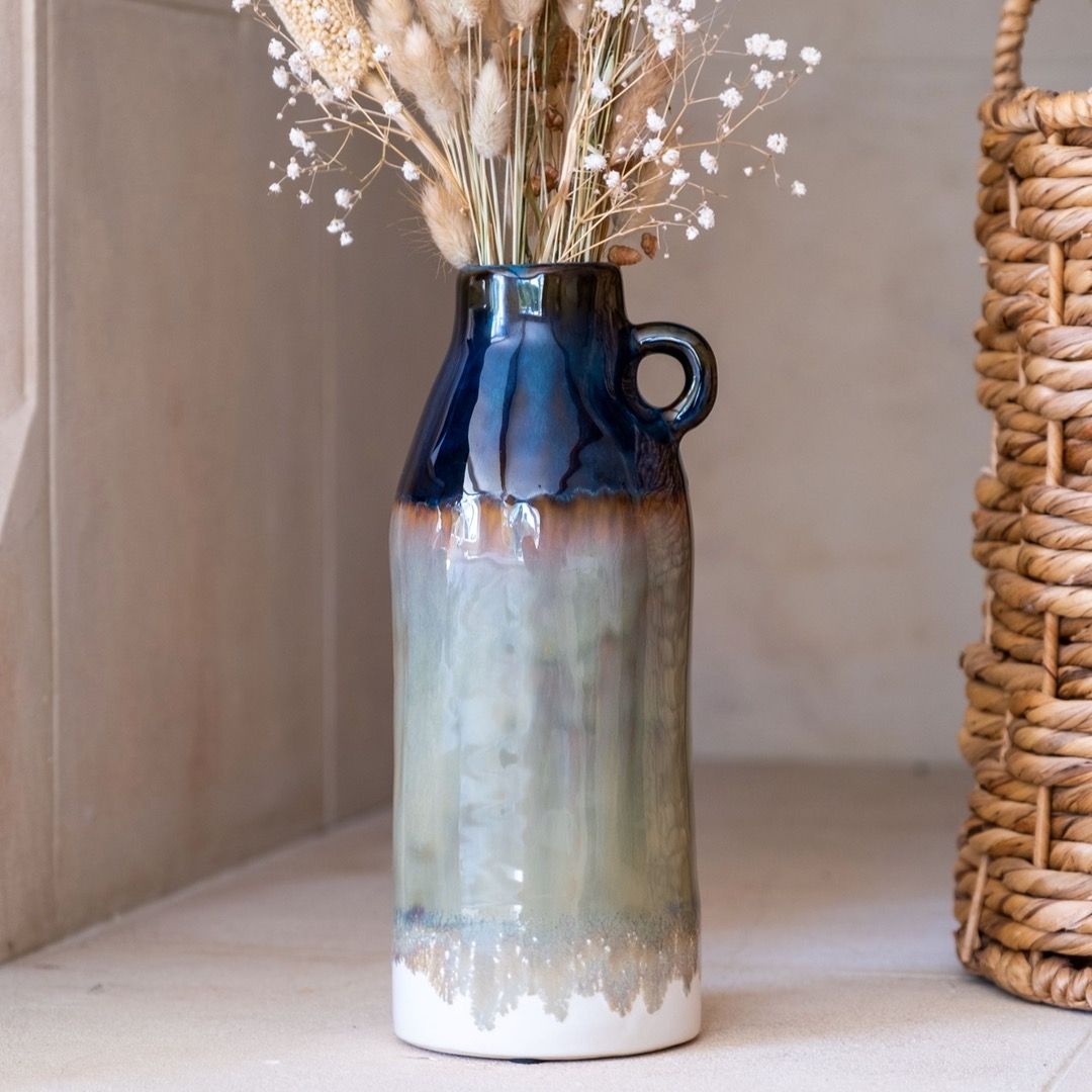 A tall, ombre glased pitcher ceramic vase with a navy top  and marbled bottom