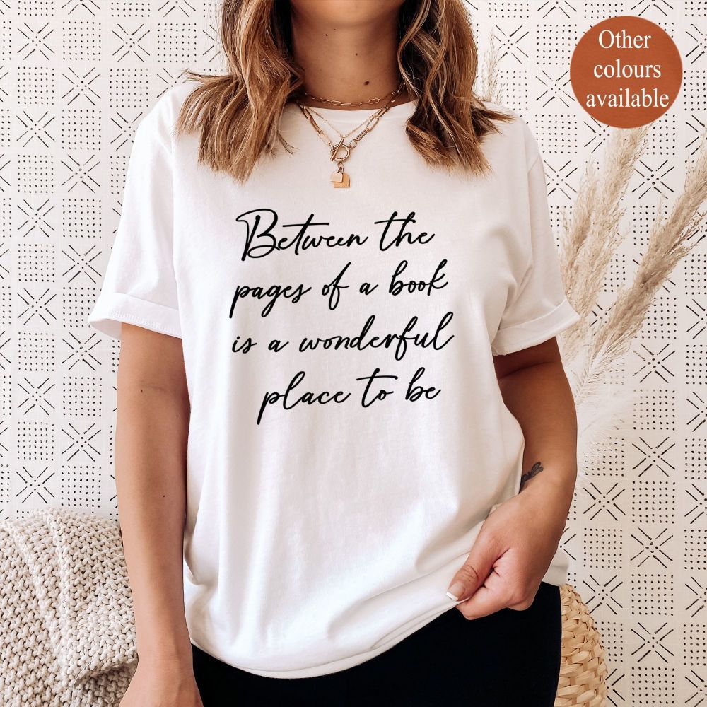 A plain white tee featuring the text "Between the pages of a book is a wonderful place to be"