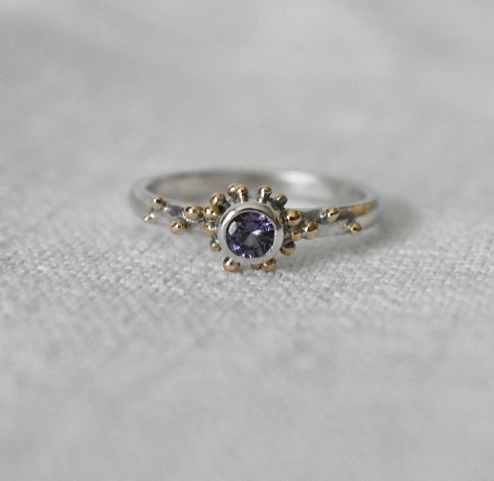 An ecosilver and gold ring featuring a purple sapphire