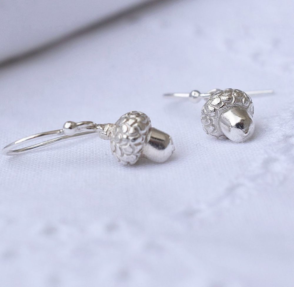 Two silver acorn earrings  against a white background