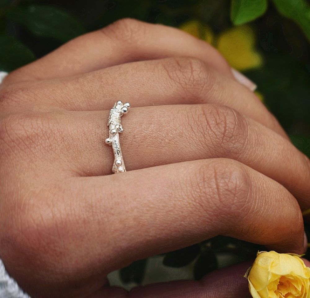 Elven Twig Ring with Silver Berries against a floral background