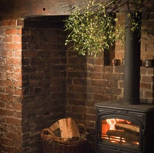 A chandelier of mistletoe hanging above a woodburner fireplace