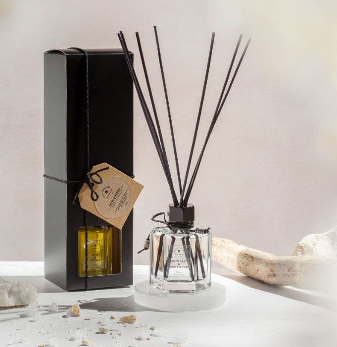 A rocksalt and driftwood reed diffuser displayed with its box and driftwood
