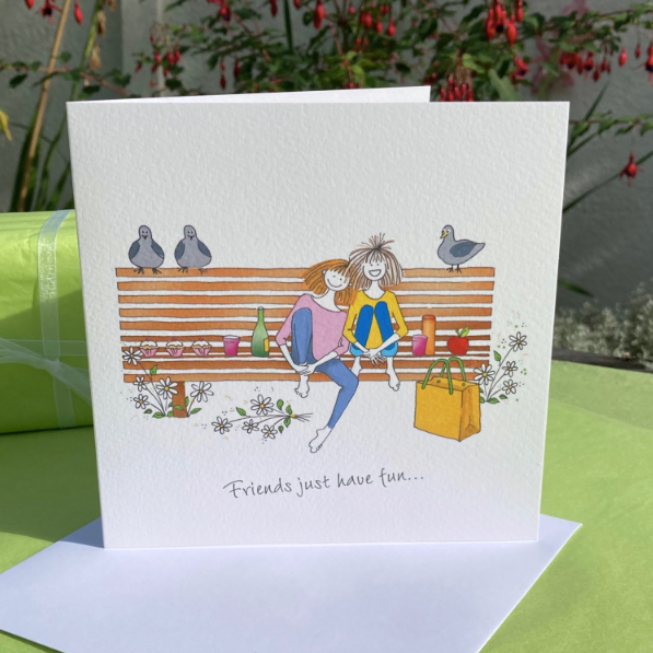 A card featuring two friends sitting on a bench surrounded by pidgeons and flowers