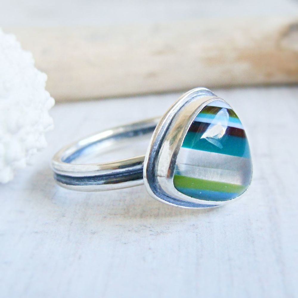 A triangle surfite pebble in layers of different colours on a sterling silver ring