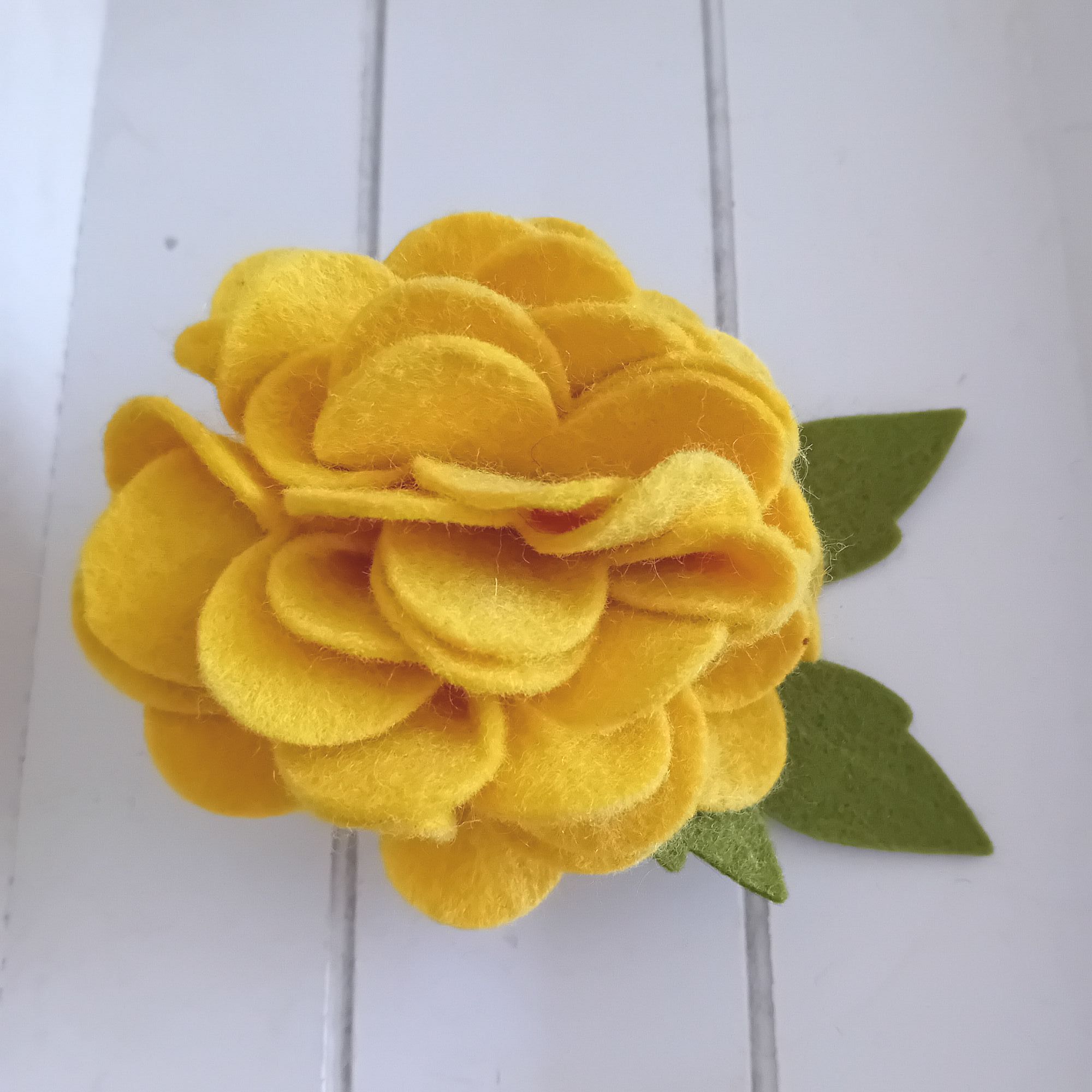 A large felt marigold brooch with its leaves