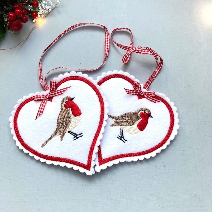 two felt heart hanging ornaments with robins embroidered on them