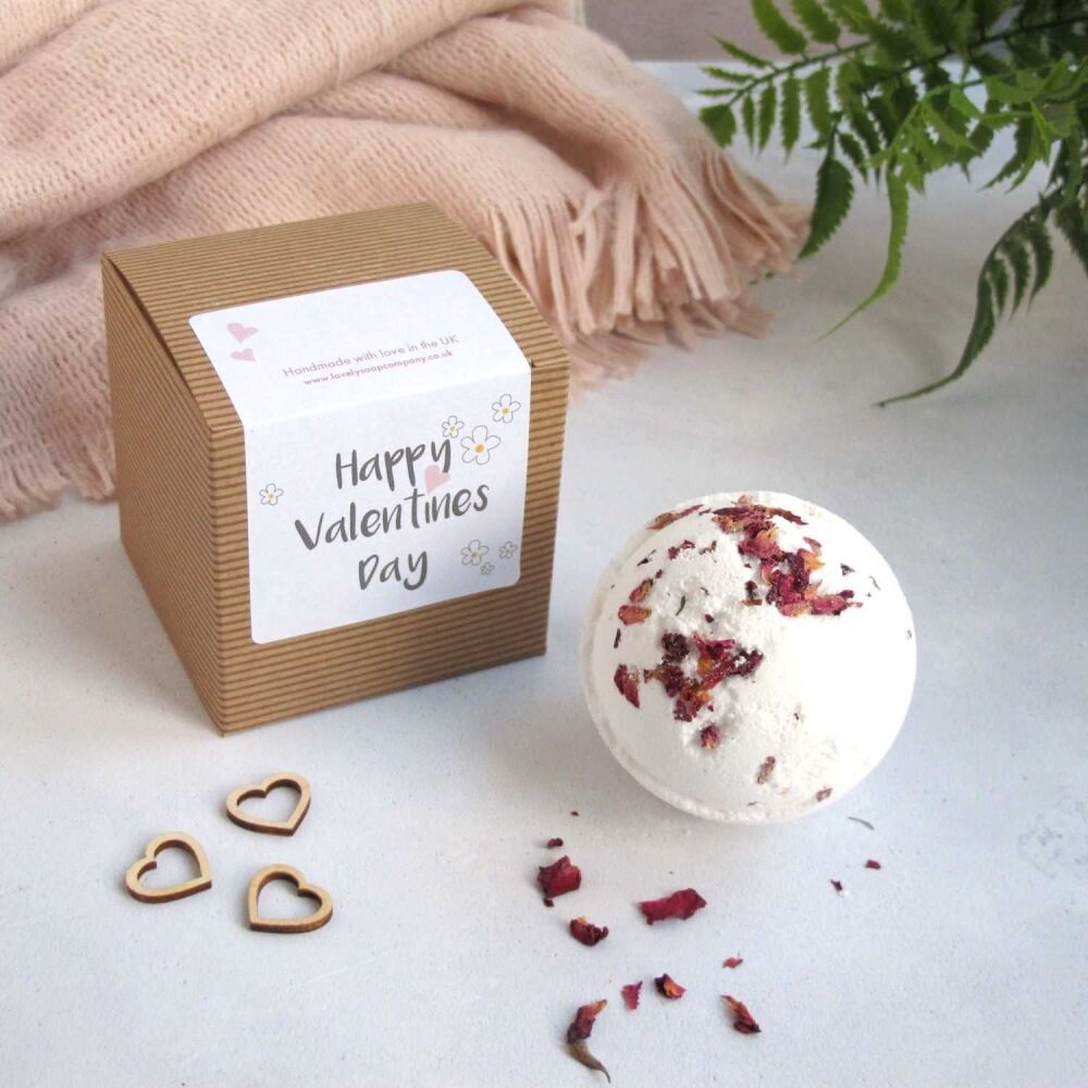 A white bath bomb with rose petals featured next to its gift box