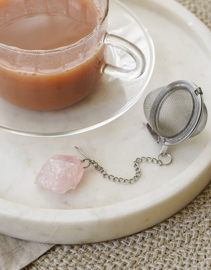 A rose quartz attached to a tea strainer by an elegant chain