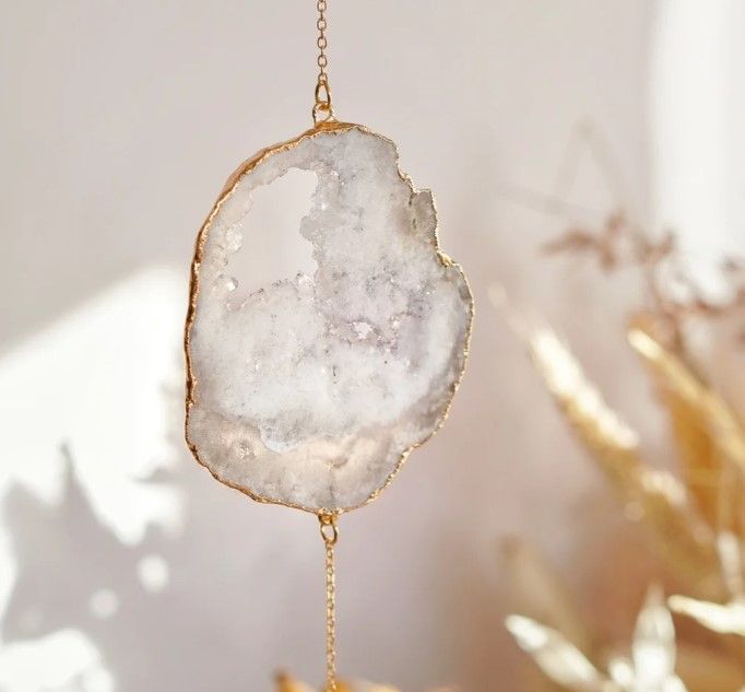 A quartz crystal framed in gold and hanging from a chain, catching the sunlight