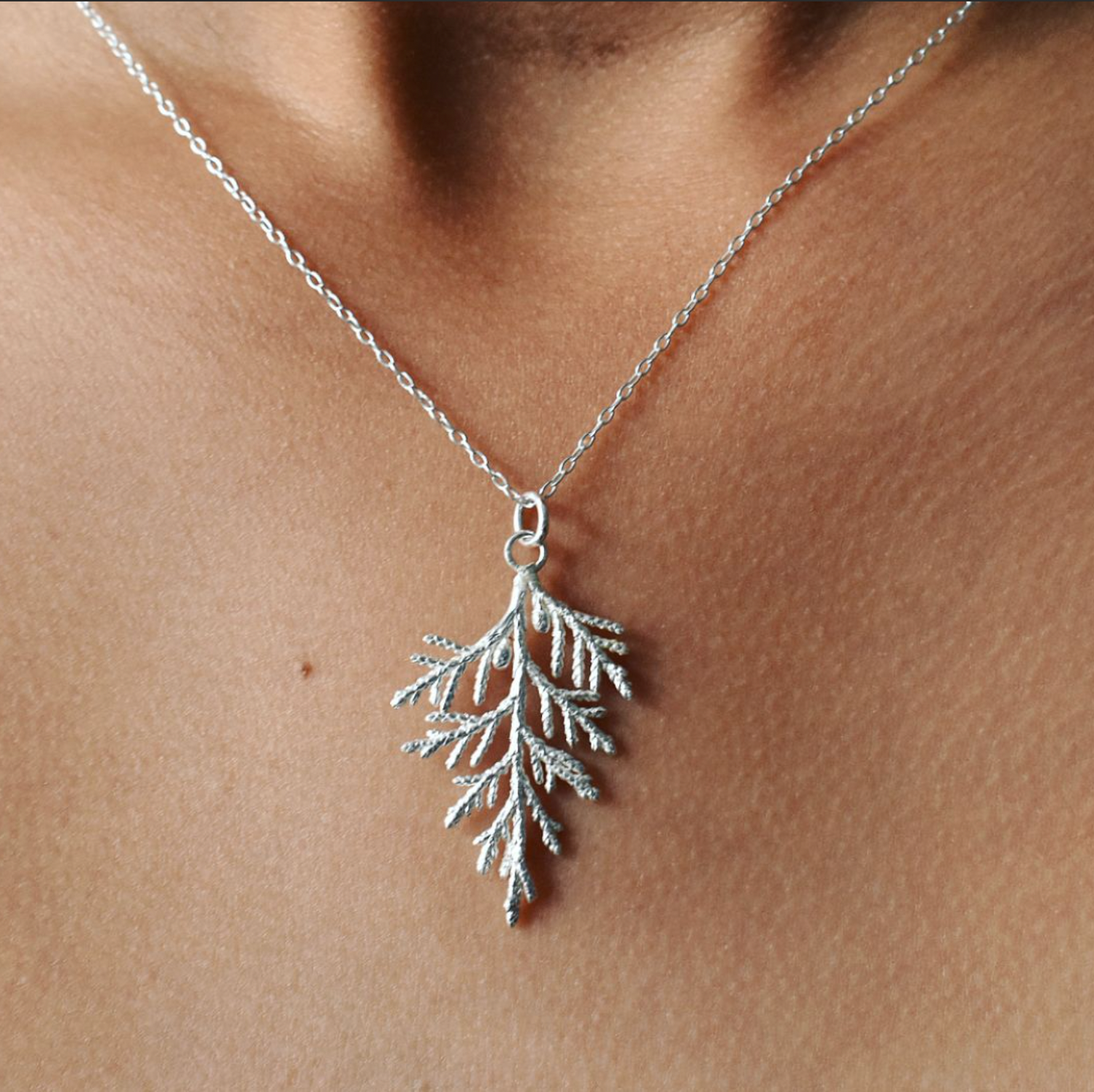 A silver woodland wreath necklace featuring leaves and berries