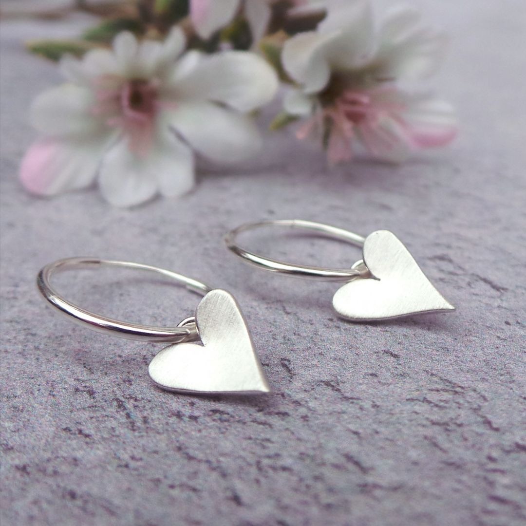 a pair of sterling silver hoop earrings, one with a moon charm and the other a star