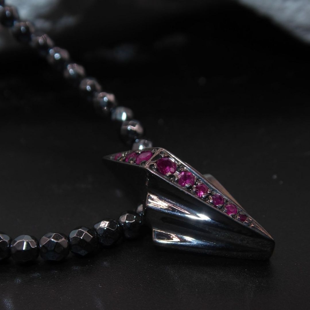 A woolen brooch featuring a rainbow rocket ship flying through a bright night sky