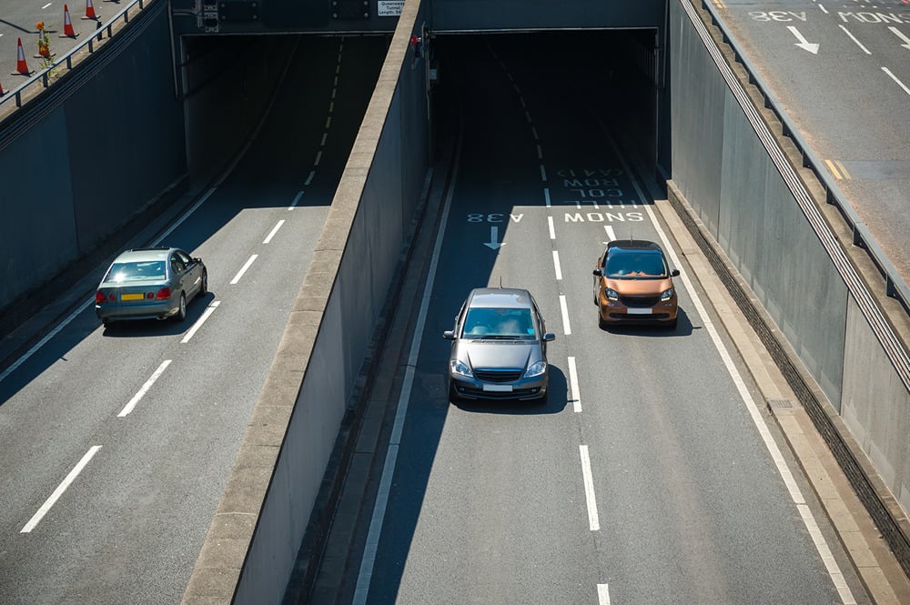 Before Entering a Tunnel  Preparation is key. As you approach, take a moment to get yourself and your vehicle ready:  Choose your lane early. Avoid last-minute changes by positioning yourself well in advance.   Switch on your headlights. Even in bright daylight, tunnels can be very dark. You need to see and be seen.   Watch for changing speed limits. Speed restrictions often alter near tunnel entrances, so stay alert to any signs on the approach or mounted above the lanes.   Stay informed. Keep your radio tuned to local traffic updates and check any electronic information boards for incidents or closures ahead.