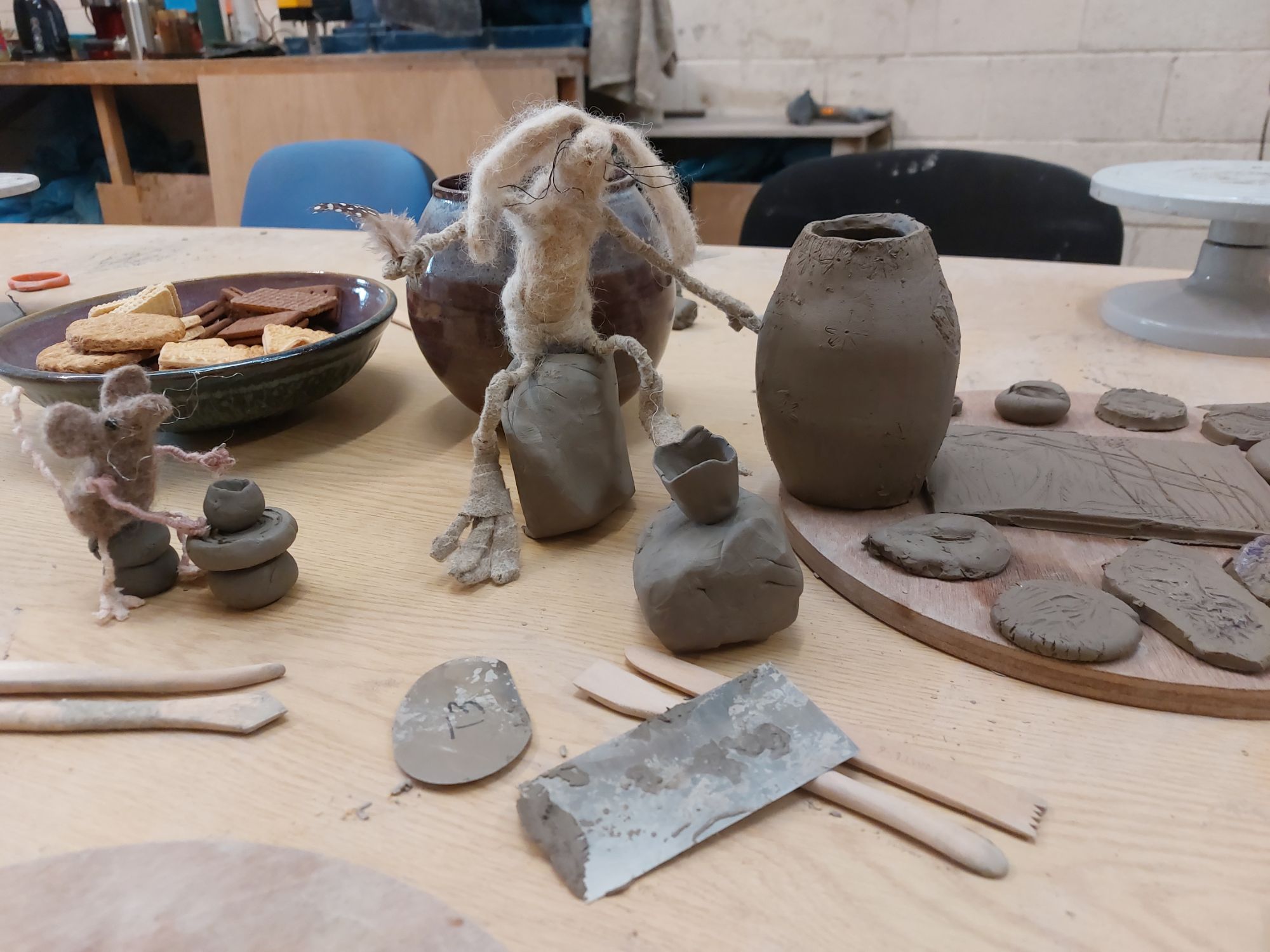 Felted hare sits amongst tiny pottery pieces