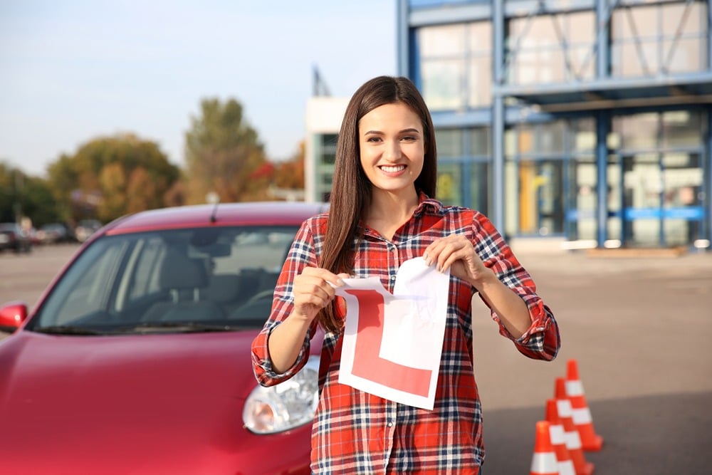 Smiling woman tearing learner driver L plate