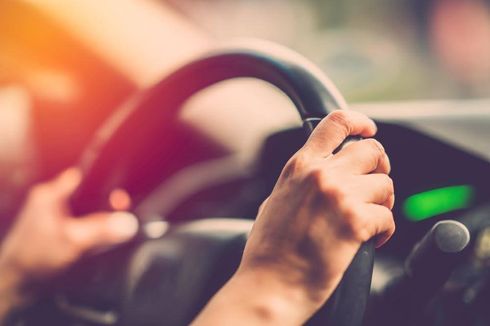 Person driving car with hands on steering wheel