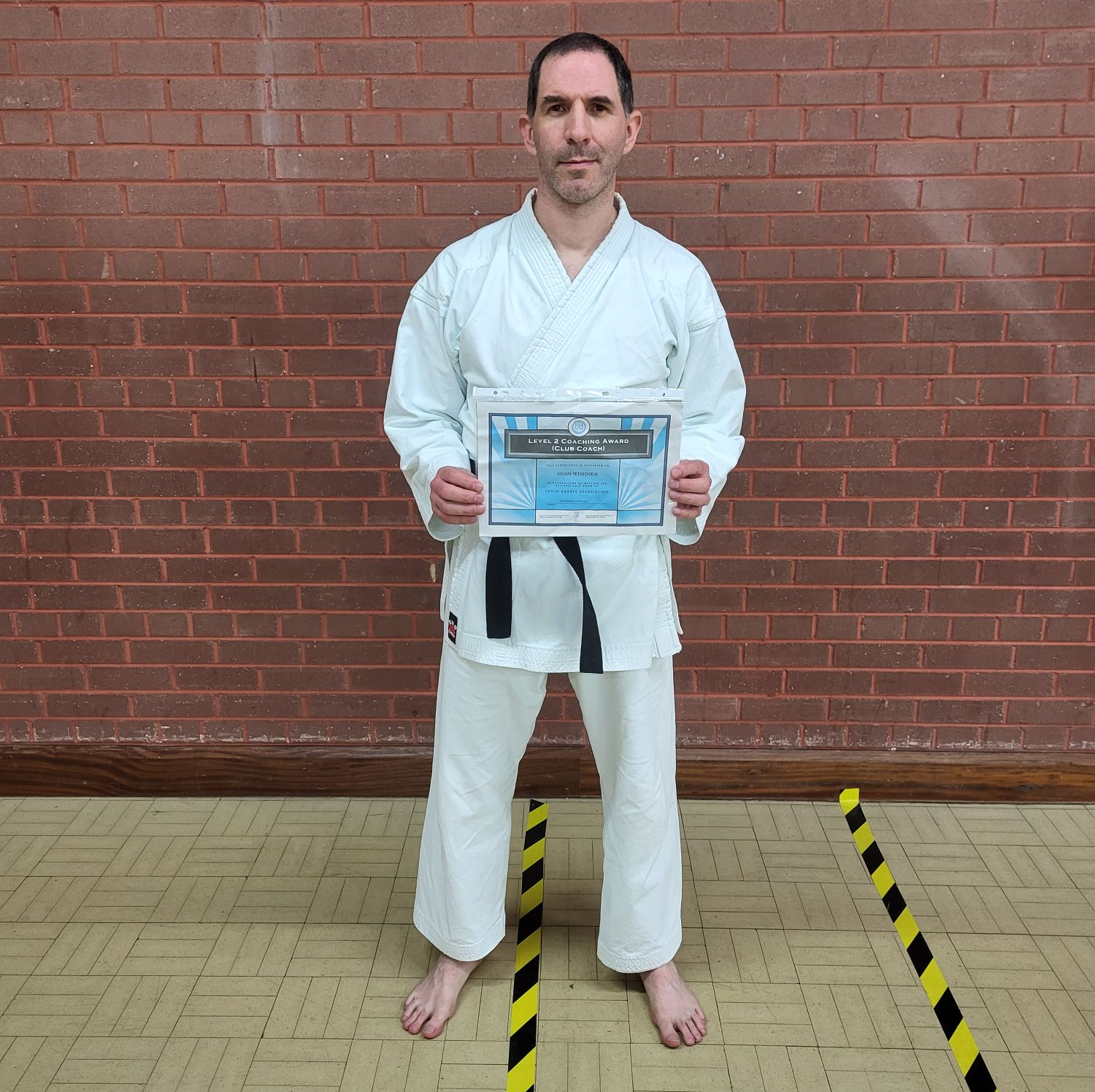 Man in karate suit holding certficate