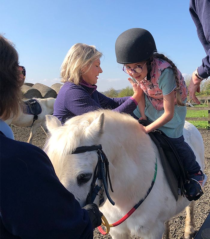 disabled child mounting white pony