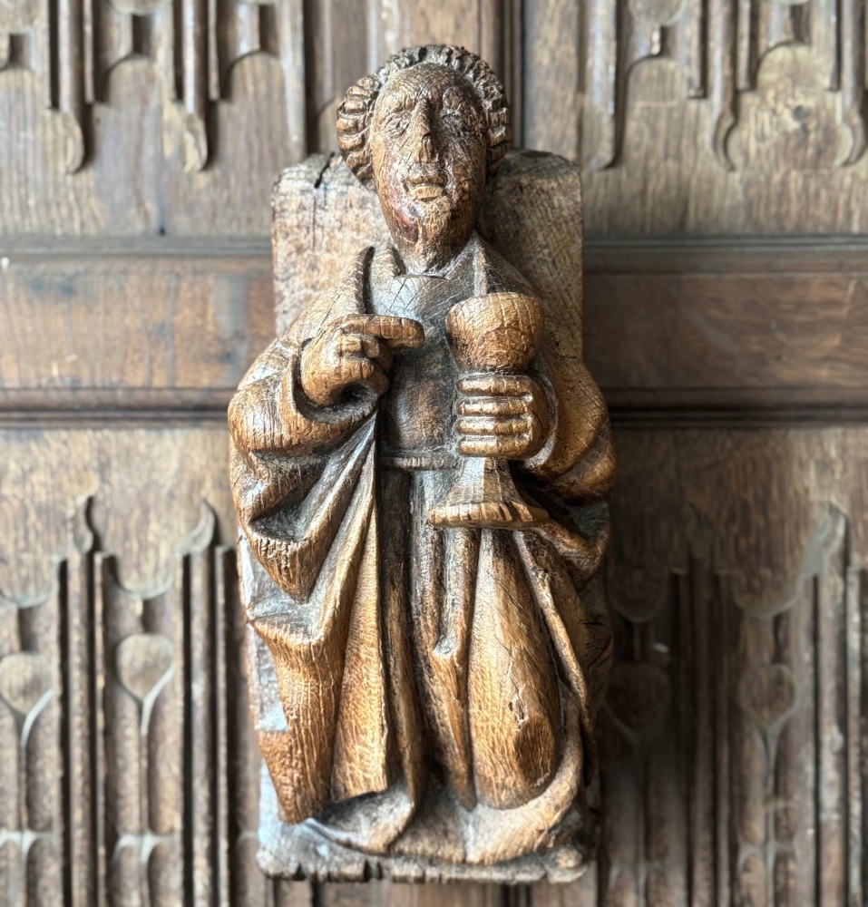 A 16th Century Carved Oak Corbel Depicting St.John Holding A Chalice