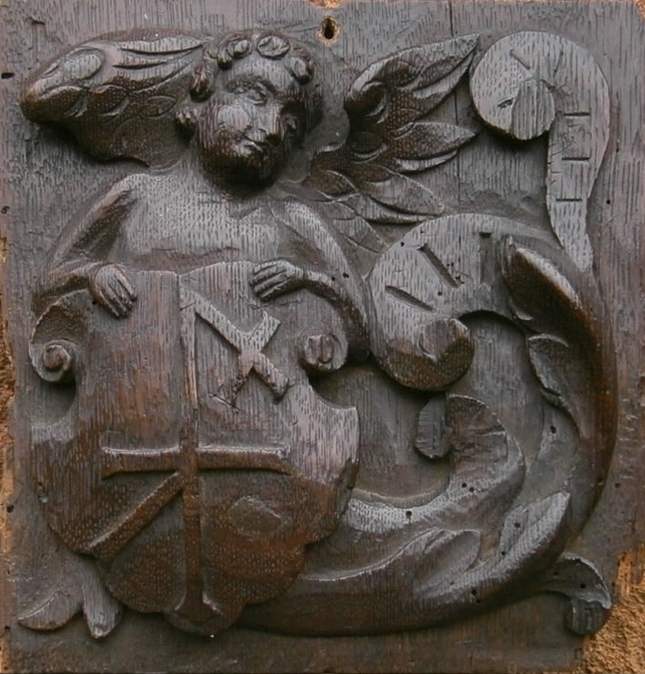 A 16th century English oak panel depicting an angel holding a shield with merchants mark