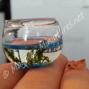 A 12th scale fish bowl filled with water with a goldfish ready to go in