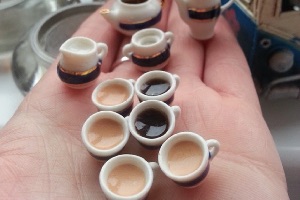 A collection of scale tea cups and coffee cups filled with tea and coffee for a model