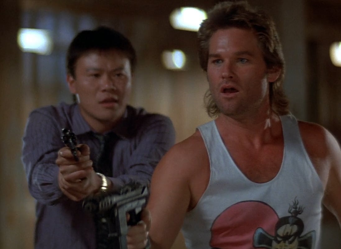 Image shows Jack Burton holding a smoking gun, startled and tense