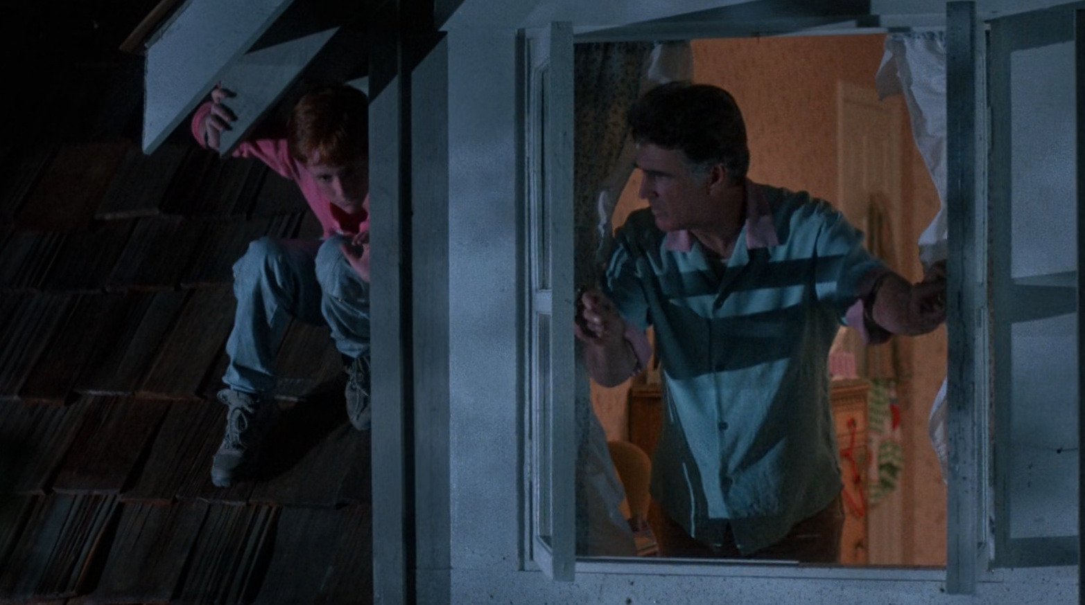 Jay Brown looking out the window while Brad hides nearby in a scene from Critters (1986)