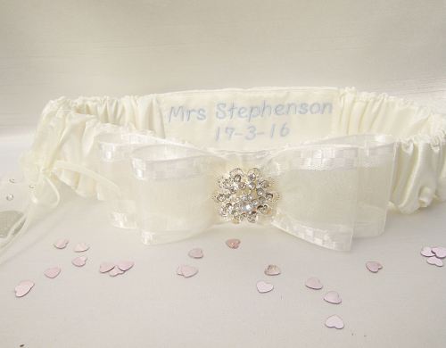 A bridal garter which has been decorated with crystals and has been personalised on the inside in a blue thread.