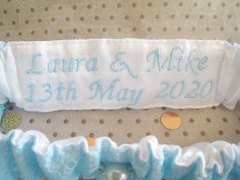 white and Blue Wedding Garter With Embroidery on the inside.