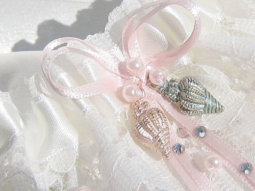 Lace Wedding Garter With shells on the front and ribbon bows in a blush pink colour.