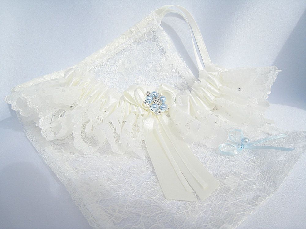 Lace bridal garter laying on a lace dust bag. Handmade With Pale Blue Pearl