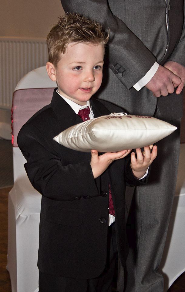 Page boy proudly holding personalised ring cushion